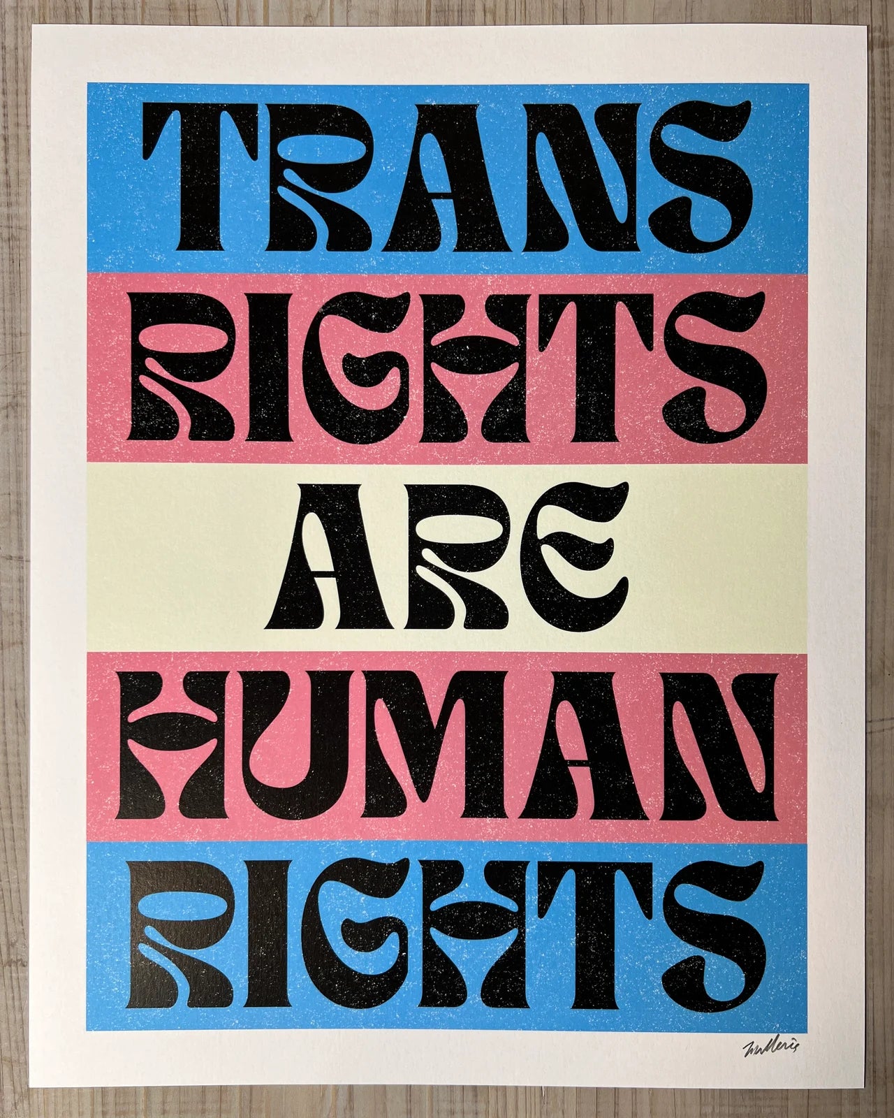 Poster with 'Trans Rights Are Human Rights' text in black on a blue, pink, and beige striped background.